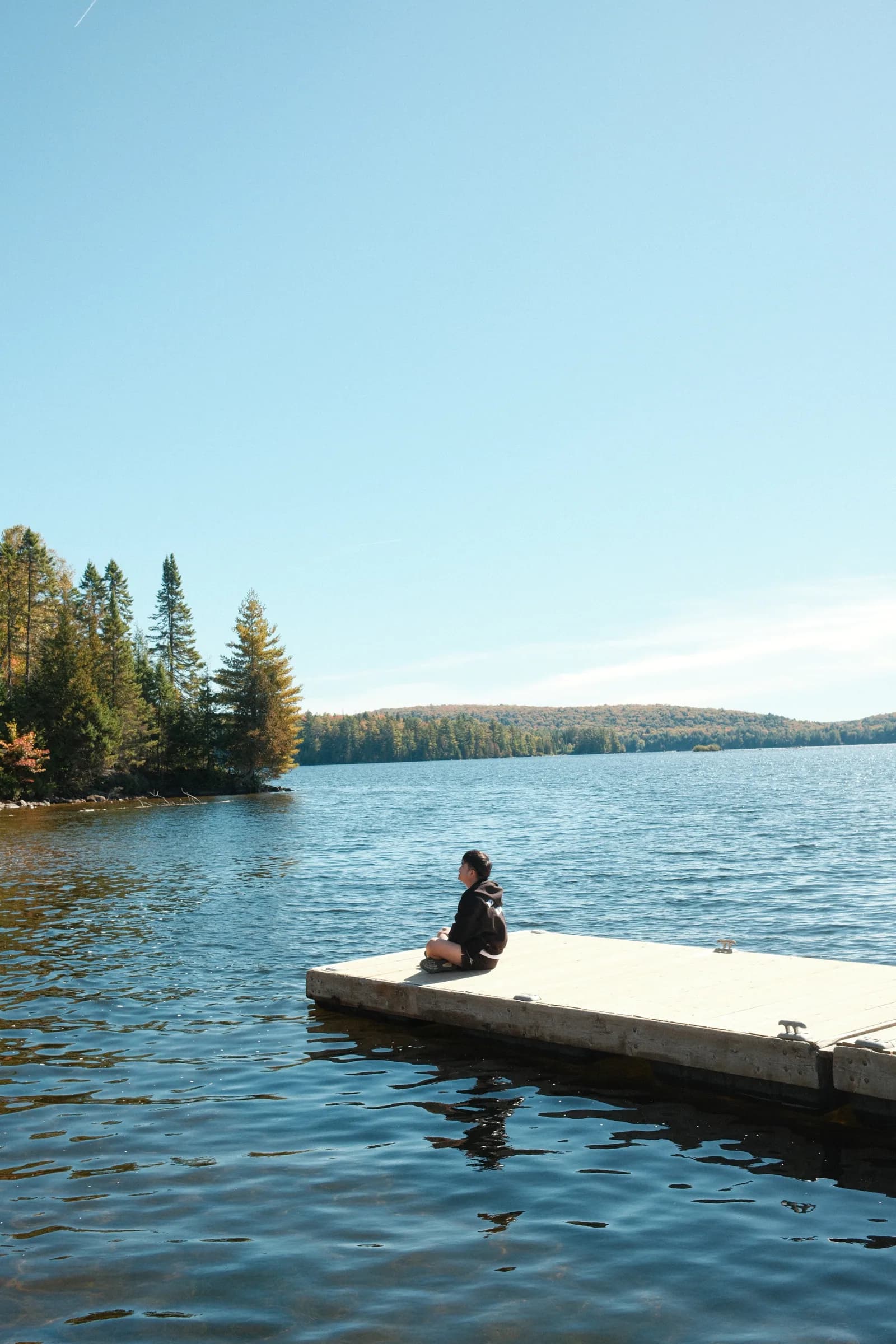 A person sitting on a dock by the lake