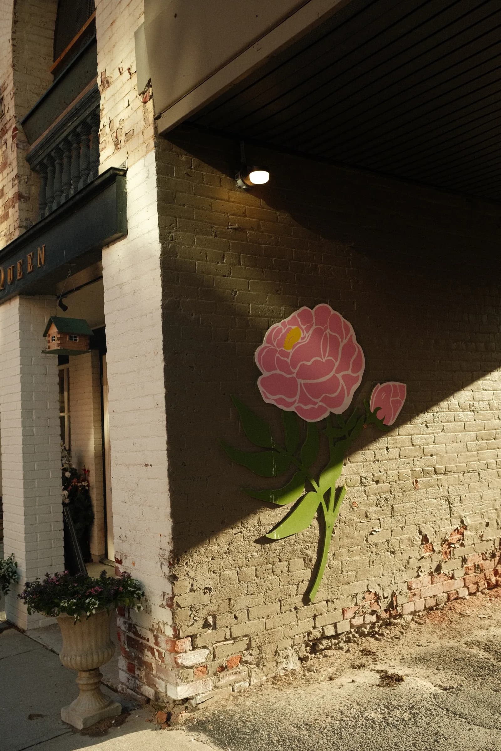 A pink flower installation catching afternoon light on a brick wall in Port Hope, Ontario